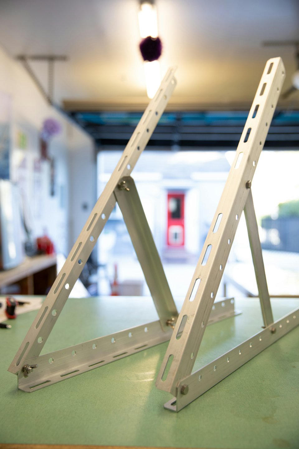 To justerbare sølvfargede metallbraketter som ligger på en arbeidsbenk.