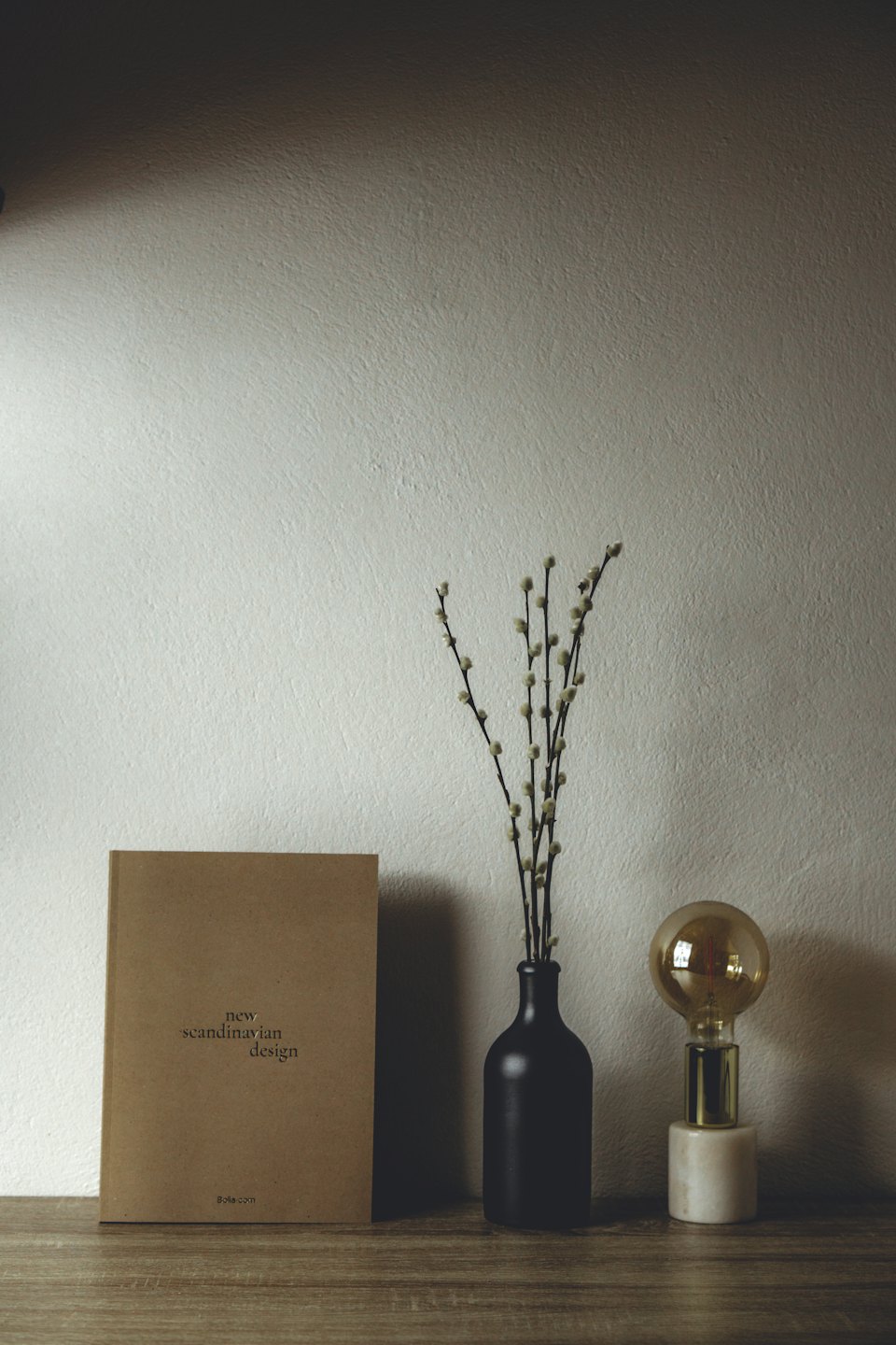 Minimalistisk hylle med bok, vase og lampe.